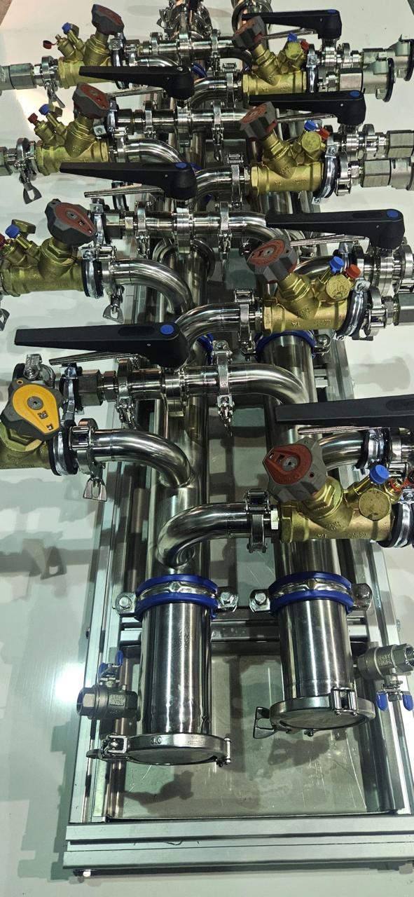 Macro detail of brass DPCV pressure valves and Tri-Clamp gasketed fittings on a stainless cooling manifold